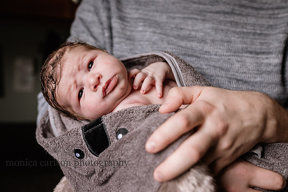 sweet baby boy wrapped in a towel and in his fathers arms by monica carlson photography