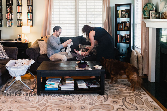 lifestyle photo of parents dressing their new baby at home in atlanta