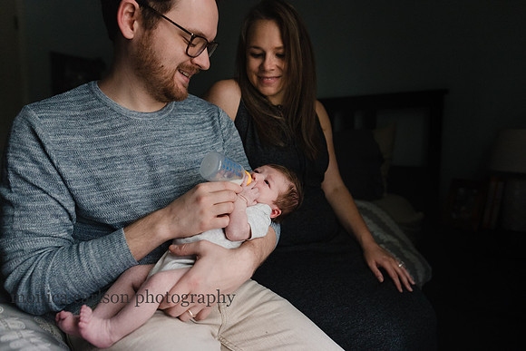 father and mother feeding their newborn son at home