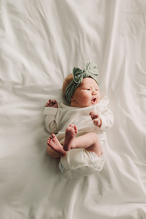 new baby lays on a bed by monica carlson