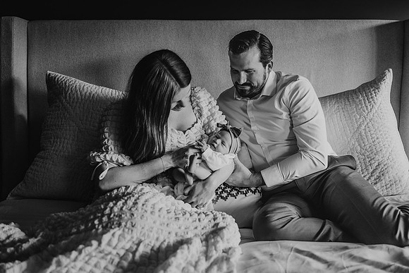 mother and father snuggle baby in their bed