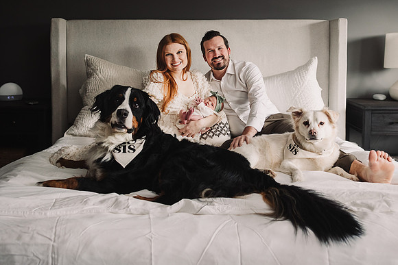 family of three and their dogs in a large bed