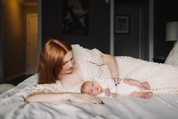 new mom lays on her side on a bed