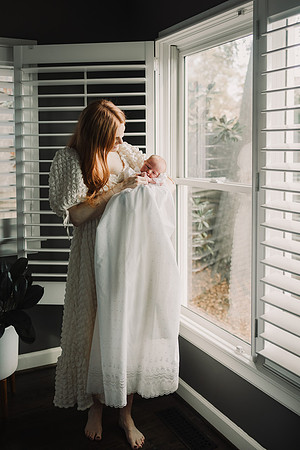mom holds baby that is wearing a baptismal dress