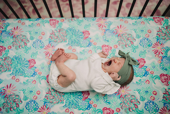 newborn baby yawns big in their crib