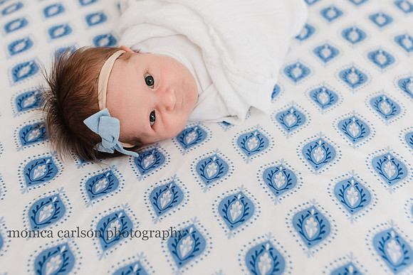 baby laying in her crib with her eyes open by monica carlson