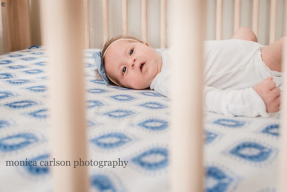 baby looking through the crib bars at Monica carlson