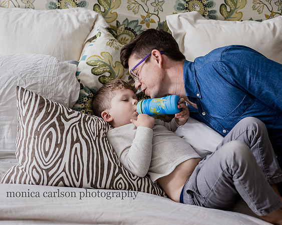 boy having a drink in bed while his dad watched him in Alpharetta