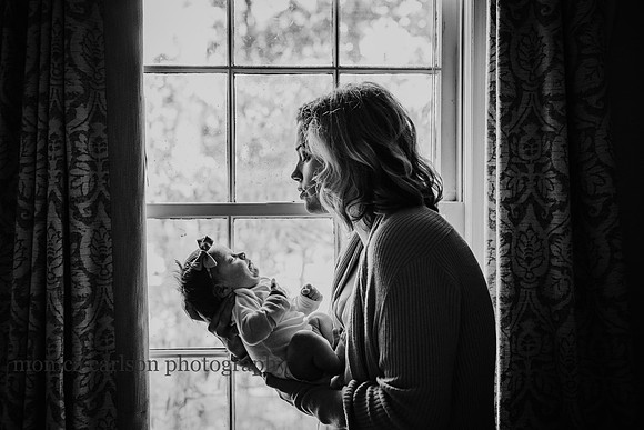 Mother holding her baby by a nursery window in alpharetta