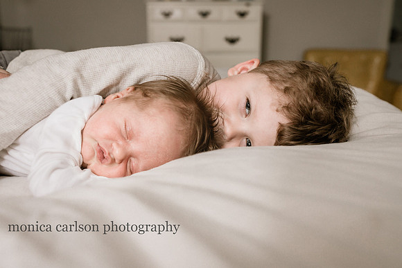mischievous little boy with a his sleeping baby sister on a bed