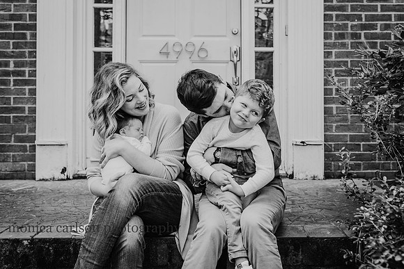 little boy making a funny face with his family outside their home