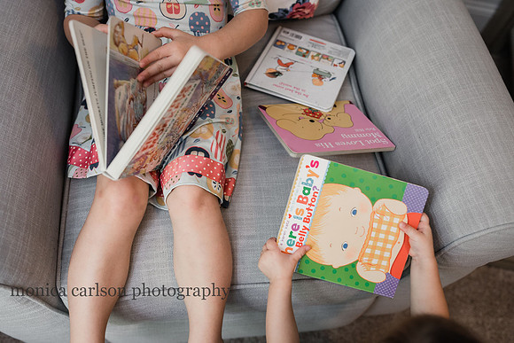a stack of familiar books being looked at by sisters at home during a photo session