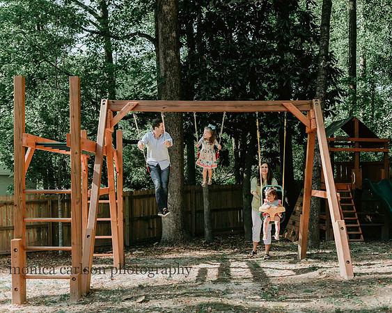 Family of four playing on their backyard playground during a home lifestyle session