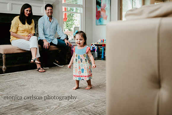 little girl dancing in her living room while her parent watch and laugh during a family photo session