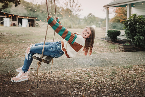 teen girl on a wooden tree swing on a farm in cumming during a family photo session