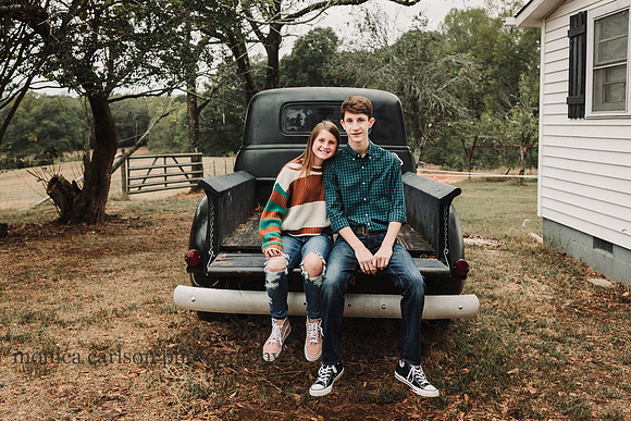 teenage brother and sister sit on the bed of a antique truck on a farm in Cumming, GA