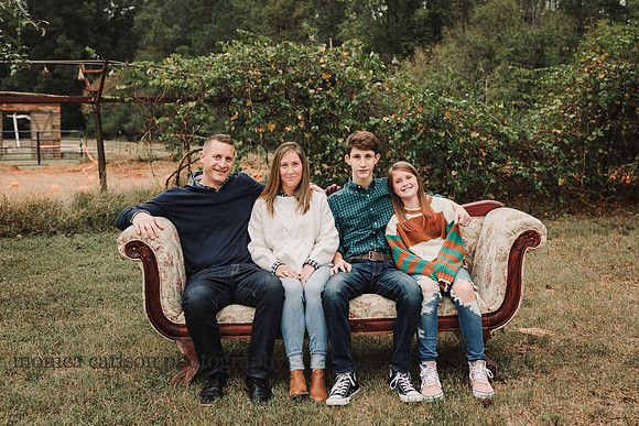 family of four sitting on a antique couch on a farm in Cumming, GA