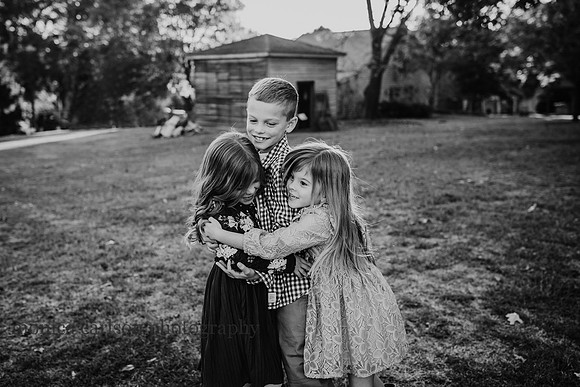 Black and white portrait of three siblings hugging in Roswell