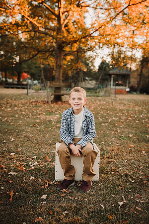 little boy sitting on a box with fall leaves behind him in Roswell, Georgia