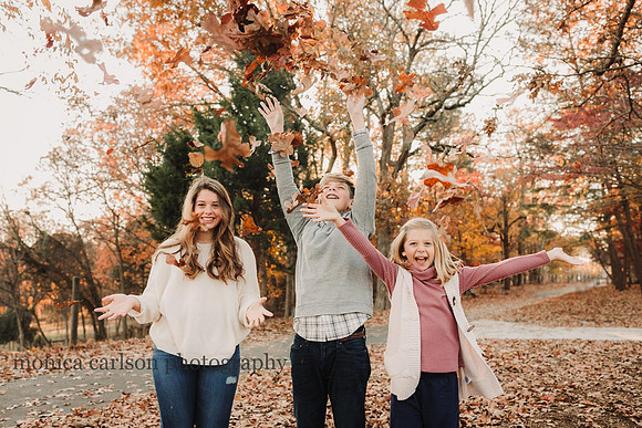 three kids enjoying throwing leaves in the fall