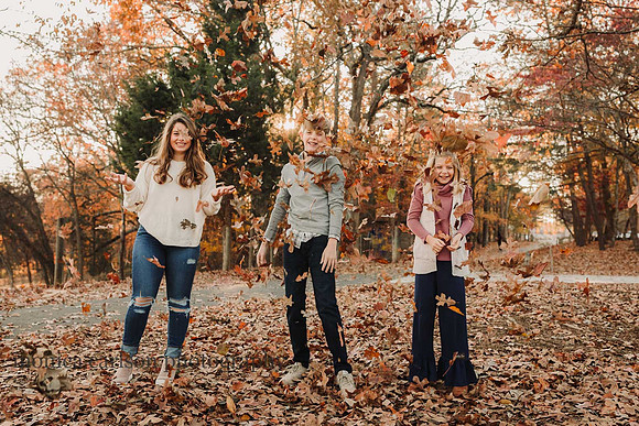 three really happy kids toss leaves in the air