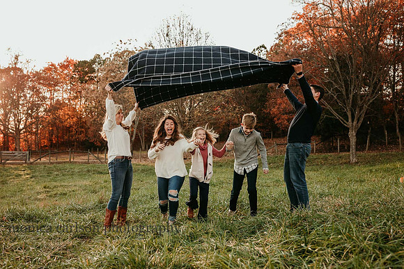 three kids run under a blanket their parents are creating a tunnel with by monica carlson