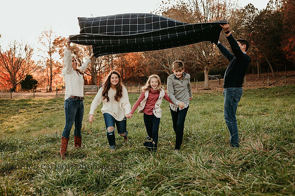 siblings run beneath a blanket their parents are creating a tunnel with