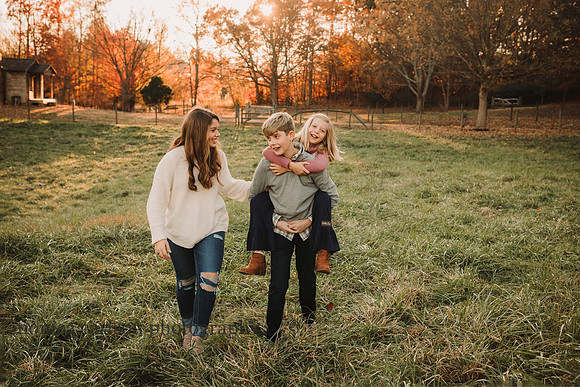 three siblings play a game of piggy back ride during a family photo session
