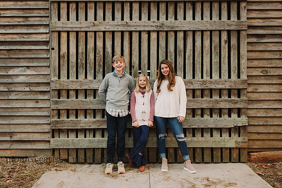 siblings standing in front of barn doors at the mcdaniel family farm