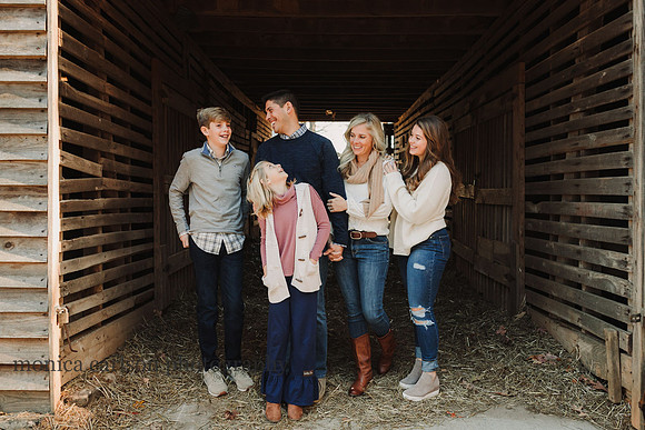 family of five sharing a laugh standing in a barn at Mcdaniell family farm