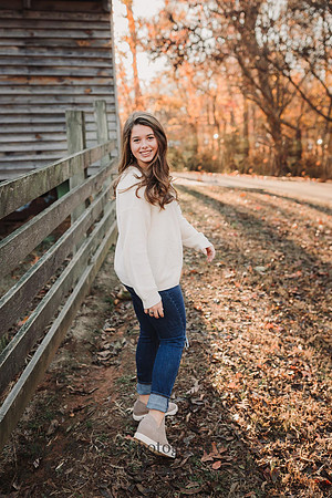 teenage girl looking over her shoulder with a barn in the background