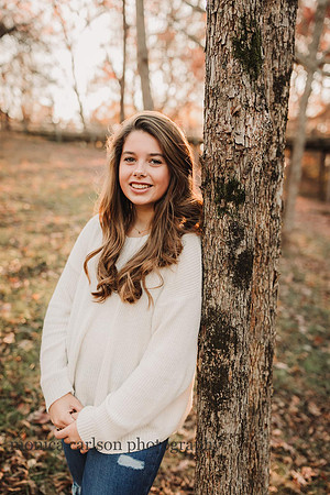 beautiful golden lit image of a teen aged girl leaning against a tree
