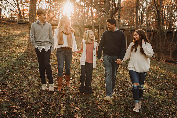 family take a sunset walk in front of a bridge during a photo session