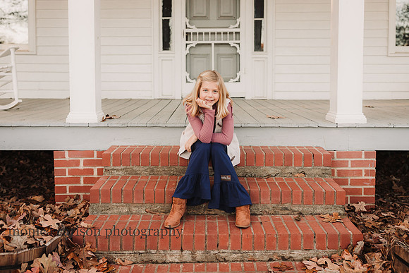 tween girl sitting on the steps of a white wooden house
