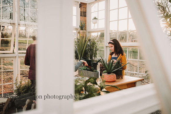 Girl contemplating her plants in a greenhouse in Lawrenceville, Georgia