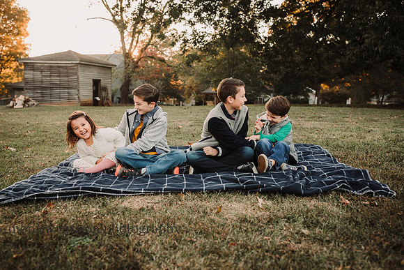 four siblings sitting on a blanket on the grounds of barrington hall