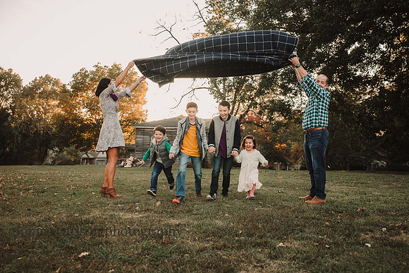 four sibling running under a blanket tunnel during a family photo session