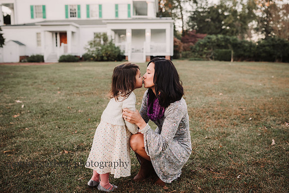 mother and daughter sharing a kiss with historic Barrington Hall in the background