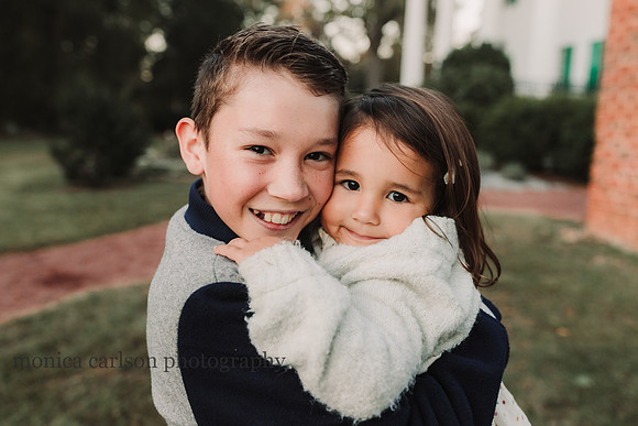 big brother snuggling his toddler sister by Monica carlson