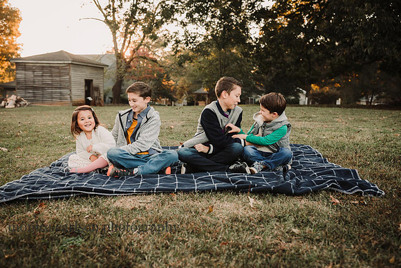 four kids sitting on a blanket tickling each other