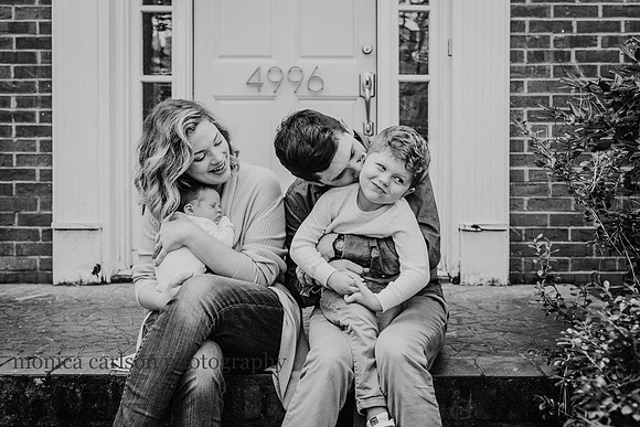 new family of four sitting on their front porch and the young boy is making a funny face