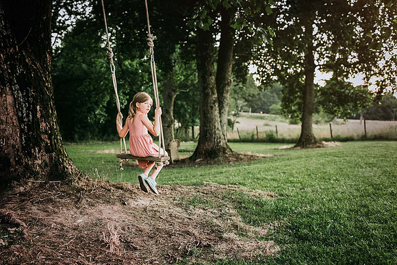 little girl sitting on a wooden tree swing on a farm in Duluth, GA