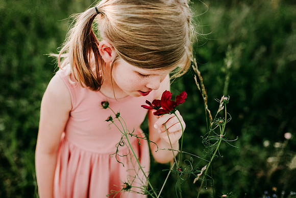 blonde girl smelling a red wild flower