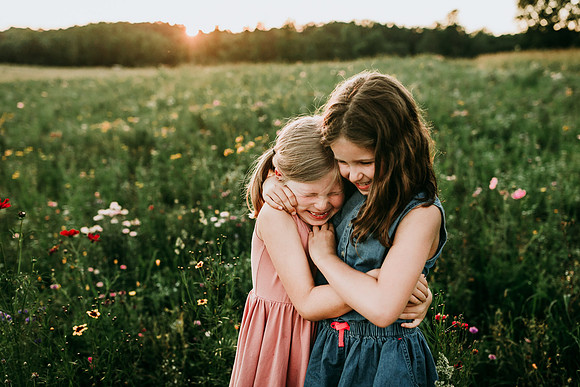 girls hugging on a wild flower field by monica carlson