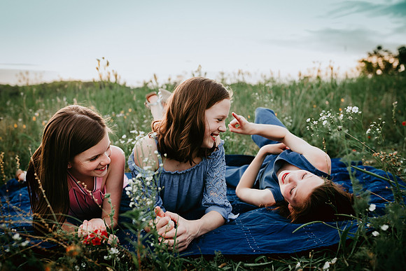 three girls laying in a field of wild flowers at prospect farms