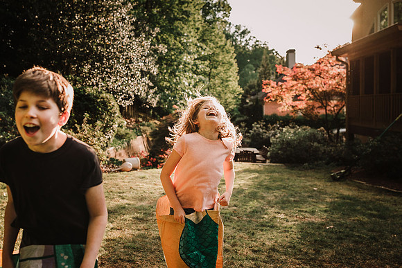 little girl laughing hysterically while having a sack race in her back yard during a quarantined