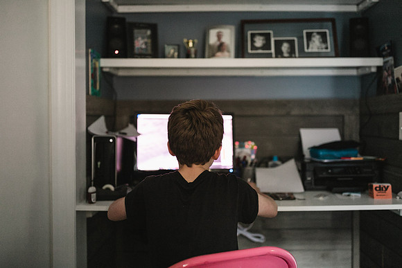 teen boy doing his school work on a computer at home during quarantine