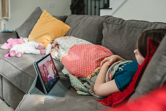 little girl listening to her teach talk during a lesson on a Ipad
