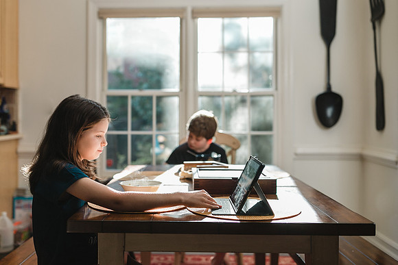 boy and his sister sitting at a table having breakfast and looking at the ipad by monica carlson