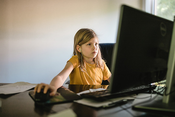 girl looking at computer doing her quarantined school work
